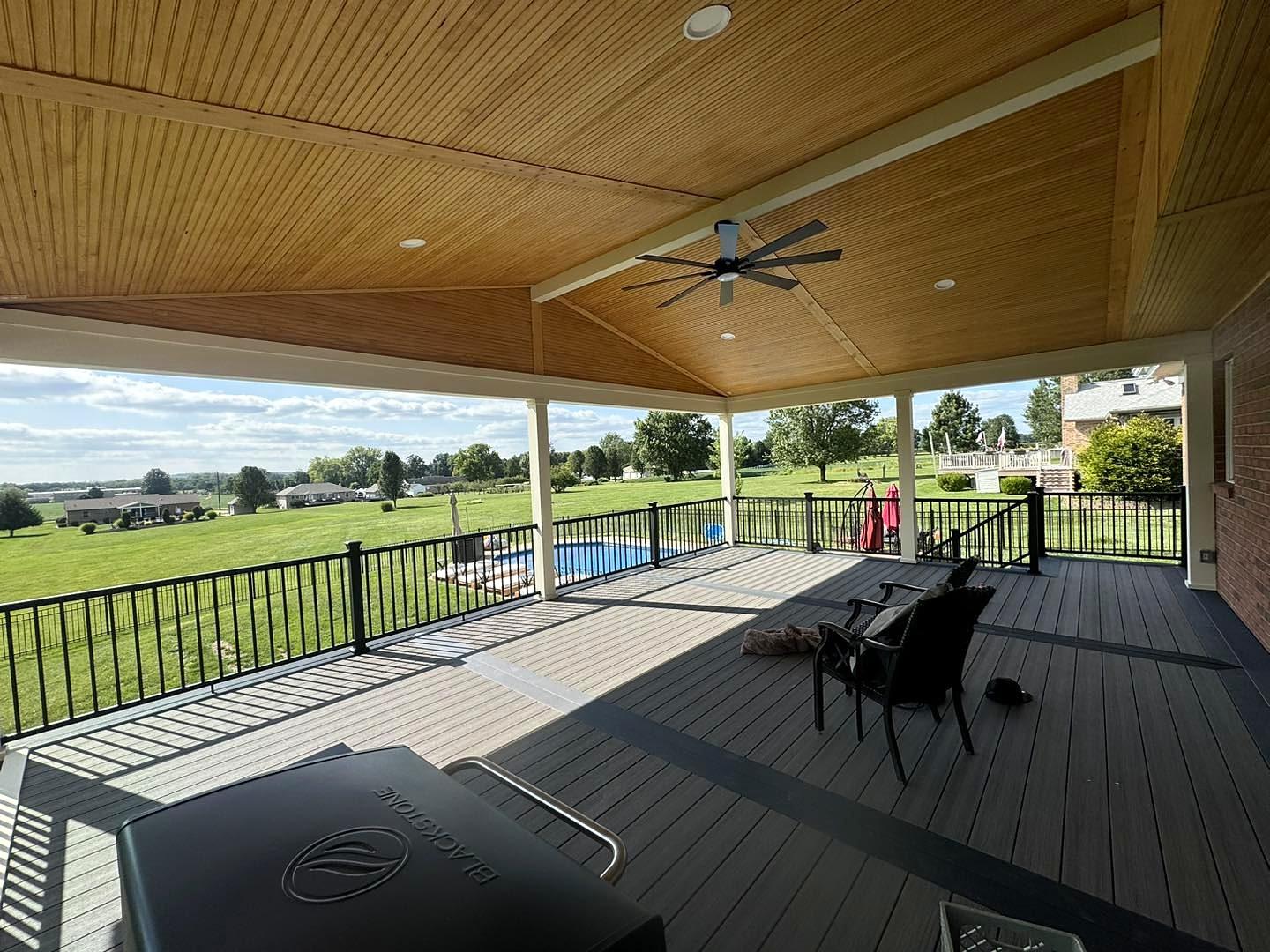 Covered composite deck with tongue-and-groove ceiling, ceiling fan and black aluminum railing overlooking the yard