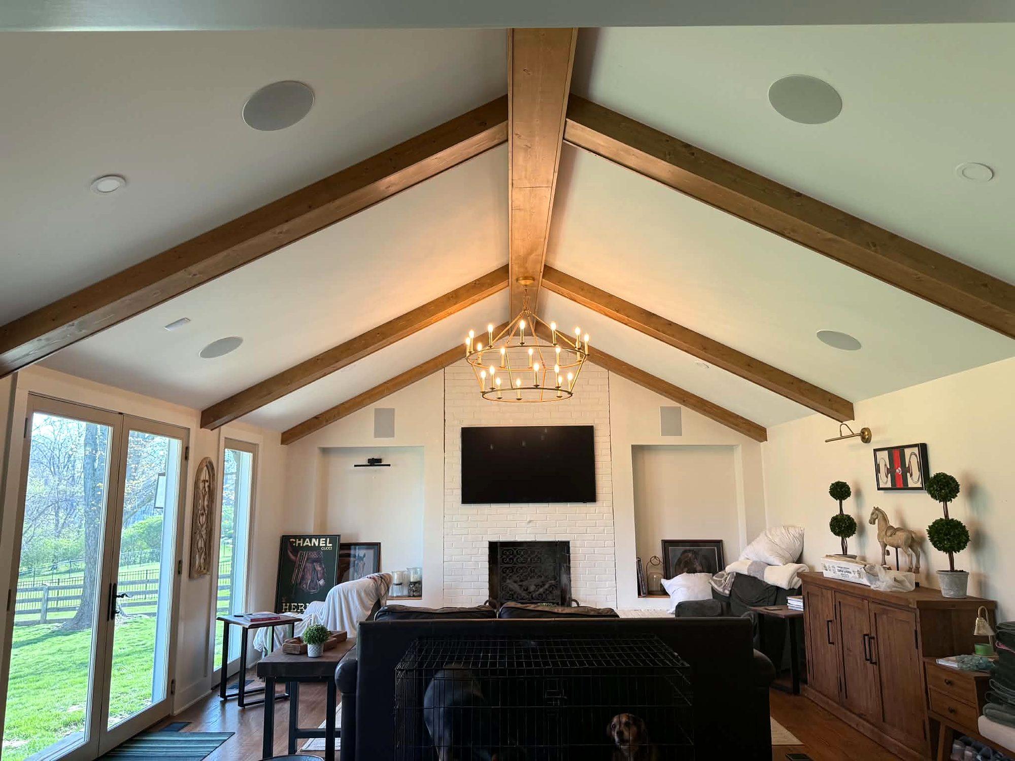 Vaulted family room with stained wood ceiling beams, a chandelier and a fireplace wall